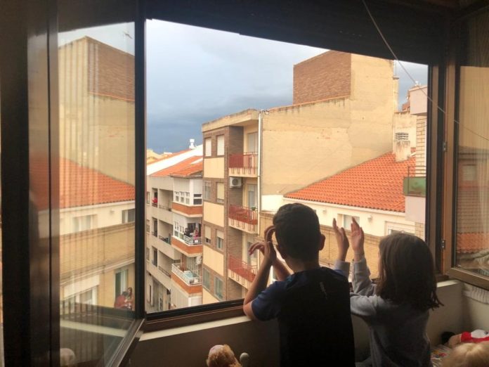 Niños aplaudiendo desde una ventana durante la pandemia del coronavirus.