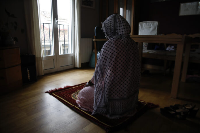 Una joven musulmana se dispone para el rezo en su dimicilio, durante el confinamiento por el coronavirus.