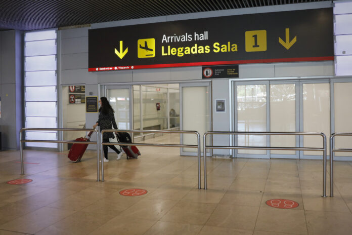 Una persona empuja dos maletas mientras abandona la sala de llegadas 1 de la Terminal 1 del Aeropuerto de Barajas, en Madrid el 4 de julio de 2020.