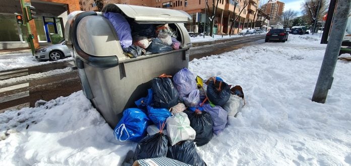 Contenedor de basura, desbordado, en una de las muy nevadas calles de Guadalajara.