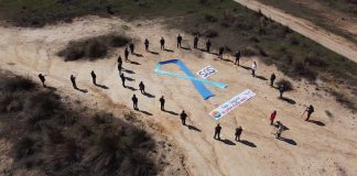 Los 22 alcaldes ribereños rodean el gran lazo azul en la playa, seca, de Entrepeñas en Sacedón.