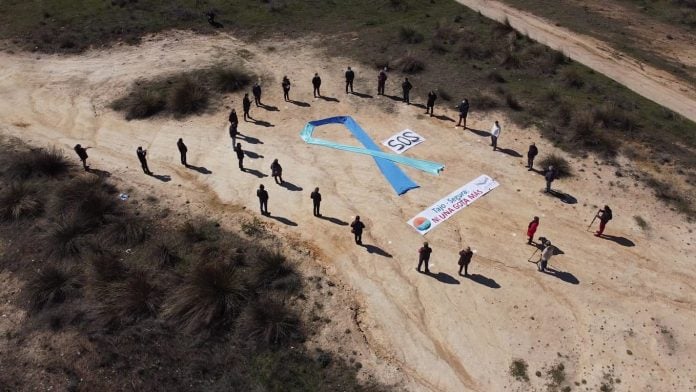 Los 22 alcaldes ribereños rodean el gran lazo azul en la playa, seca, de Entrepeñas en Sacedón.