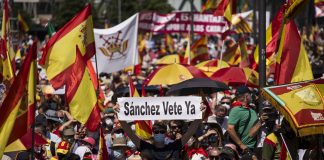 Un hombre con un cartel en el que se lee: `Sánchez vete ya´, entre una multitud de personas con banderas de España. (Foto: Alejandro Martínez Vélez / Europa Press)