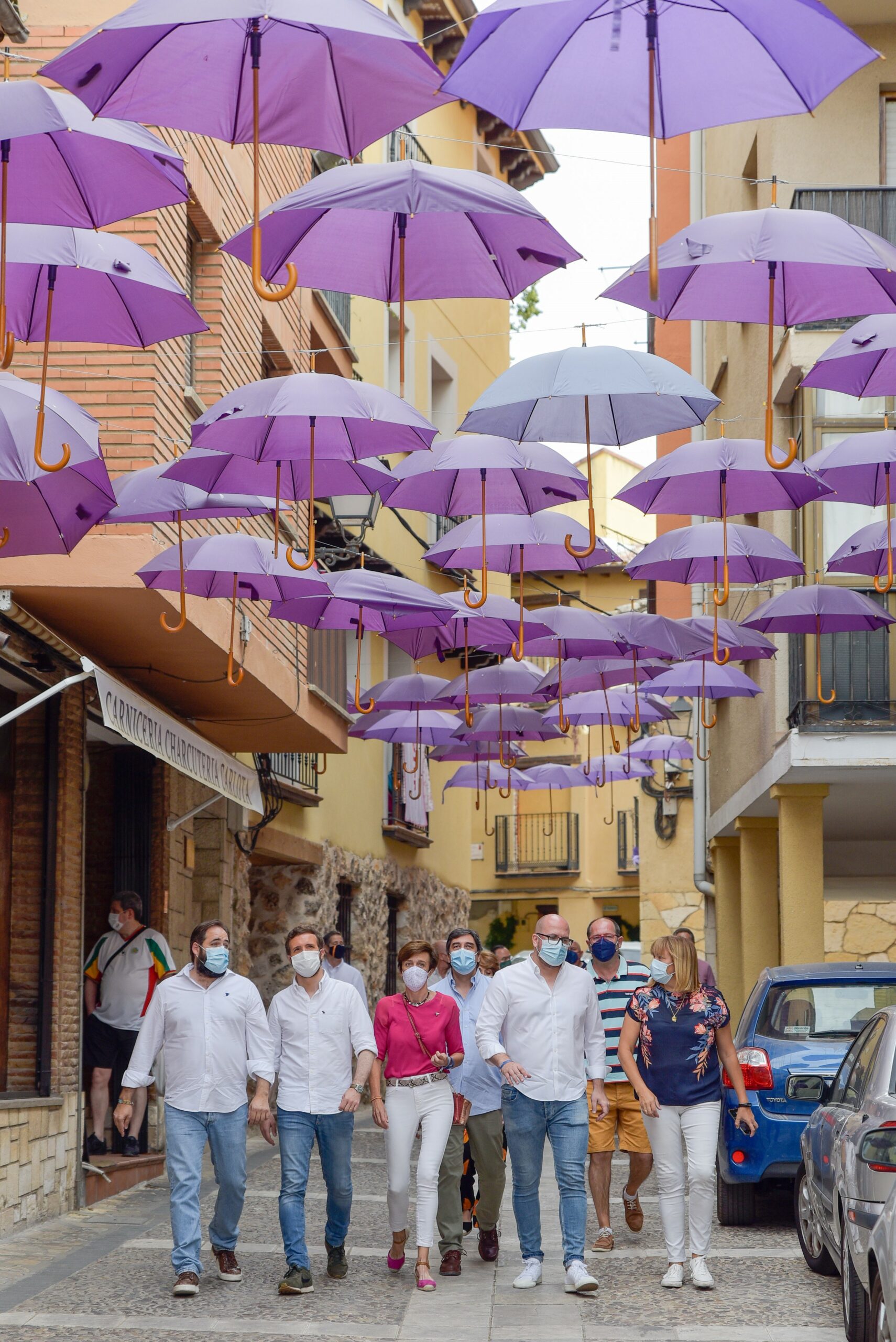 Pablo Casado y su comitiva en una de las calles de Brihuega, adornada con paraguas. (Foto: Rafa Martín/EP)