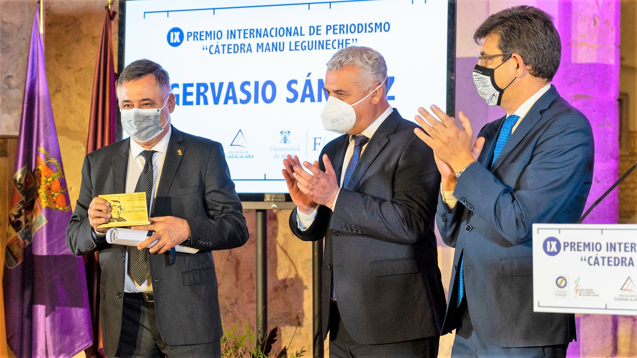 Gervasio Sánchez recibe el premio "Manu Leguineche" de manos y con los aplausos de José Luis Vega y Carmelo García. 
