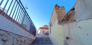 Como si fuera un bodegón urbanístico de la Guadalajara de hoy: balaustrada en desuso sobre una calle de intenso tráfico, escalera infrautilizada y uno de los numerosos solares de la ciudad. Al fondo, el Colegio de Arquitectos, en imagen captada el 31 de enero de 2023. (Foto: La Crónic@)