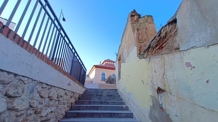 Como si fuera un bodegón urbanístico de la Guadalajara de hoy: balaustrada en desuso sobre una calle de intenso tráfico, escalera infrautilizada y uno de los numerosos solares de la ciudad. Al fondo, el Colegio de Arquitectos, en imagen captada el 31 de enero de 2023. (Foto: La Crónic@)