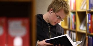 Joven leyendo en una biblioteca.