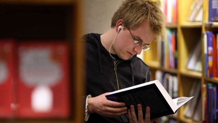 Joven leyendo en una biblioteca.