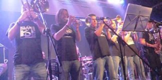 Disfruta de la charanga «Klandestinos» y apláudeles por el premio que van a recibir en el Día de la Región Klandestinos, sobre el escenario.