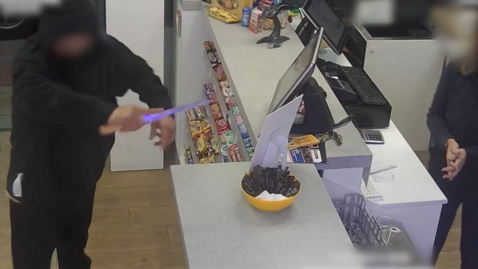 Uno de los detenidos, en pleno atraco de una gasolinera, enarbolando el cuchillo que usaba como 