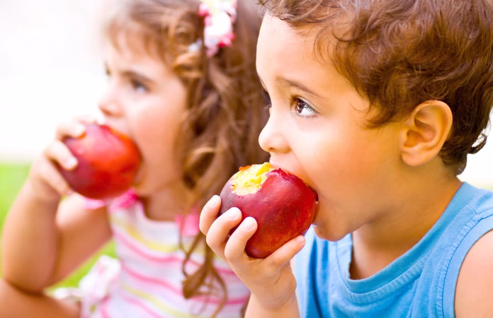 Niños comiendo fruta.