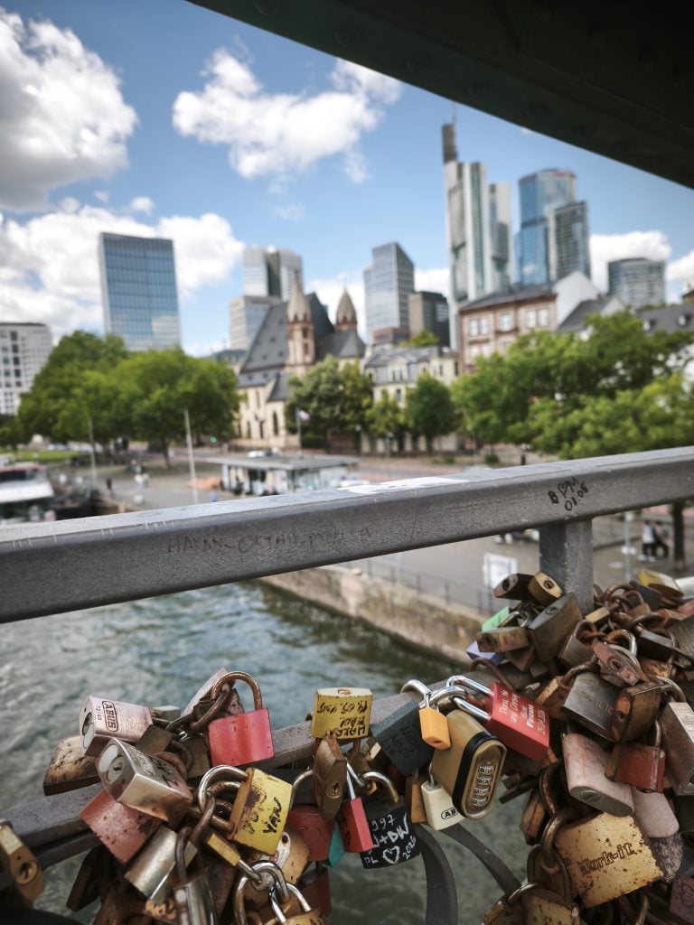 Candados en la baranda del puente de hierro sobre el Meno, en Frankfurt, con la ciudad financiera al fondo. (Foto: Jesús Orea)