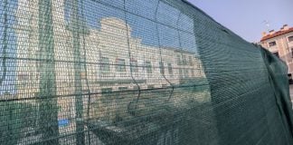Para Guarinos «Guadalajara es la mejor ciudad del mundo para vivir» El Ayuntamiento de Guadalajara tras las vallas de la inacabable obra sobre el salón de plenos, inutilizado por unas goteras en septiembre de 2023. La imagen es de julio de 2026. (Foto: La Crónic@)