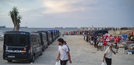 Varios inmigrantes hacen cola para que les den comida en una playa, el 19 de agosto de 2026, en Ceuta. (Foto: EP)