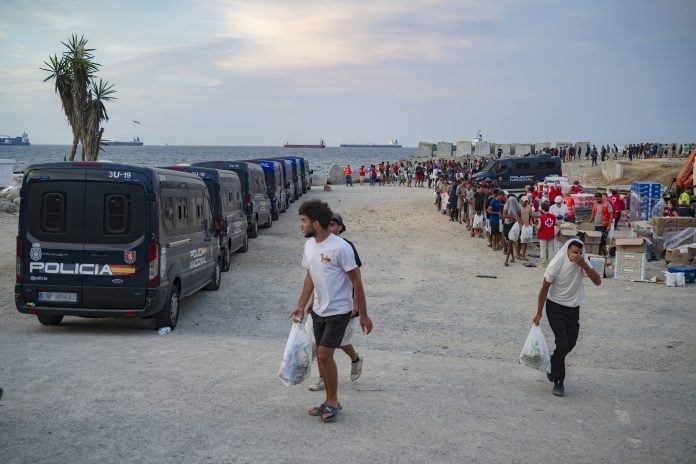 Varios inmigrantes hacen cola para que les den comida en una playa, el 19 de agosto de 2026, en Ceuta. (Foto: EP)