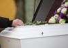Del tanatorio al cementerio: el recorrido que las familias madrileñas y barcelonesas desconocen A closeup shot of a person hand on a casket with a blurred background