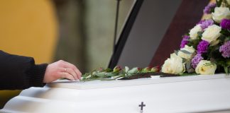 Del tanatorio al cementerio: el recorrido que las familias madrileñas y barcelonesas desconocen A closeup shot of a person hand on a casket with a blurred background