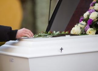 Del tanatorio al cementerio: el recorrido que las familias madrileñas y barcelonesas desconocen A closeup shot of a person hand on a casket with a blurred background